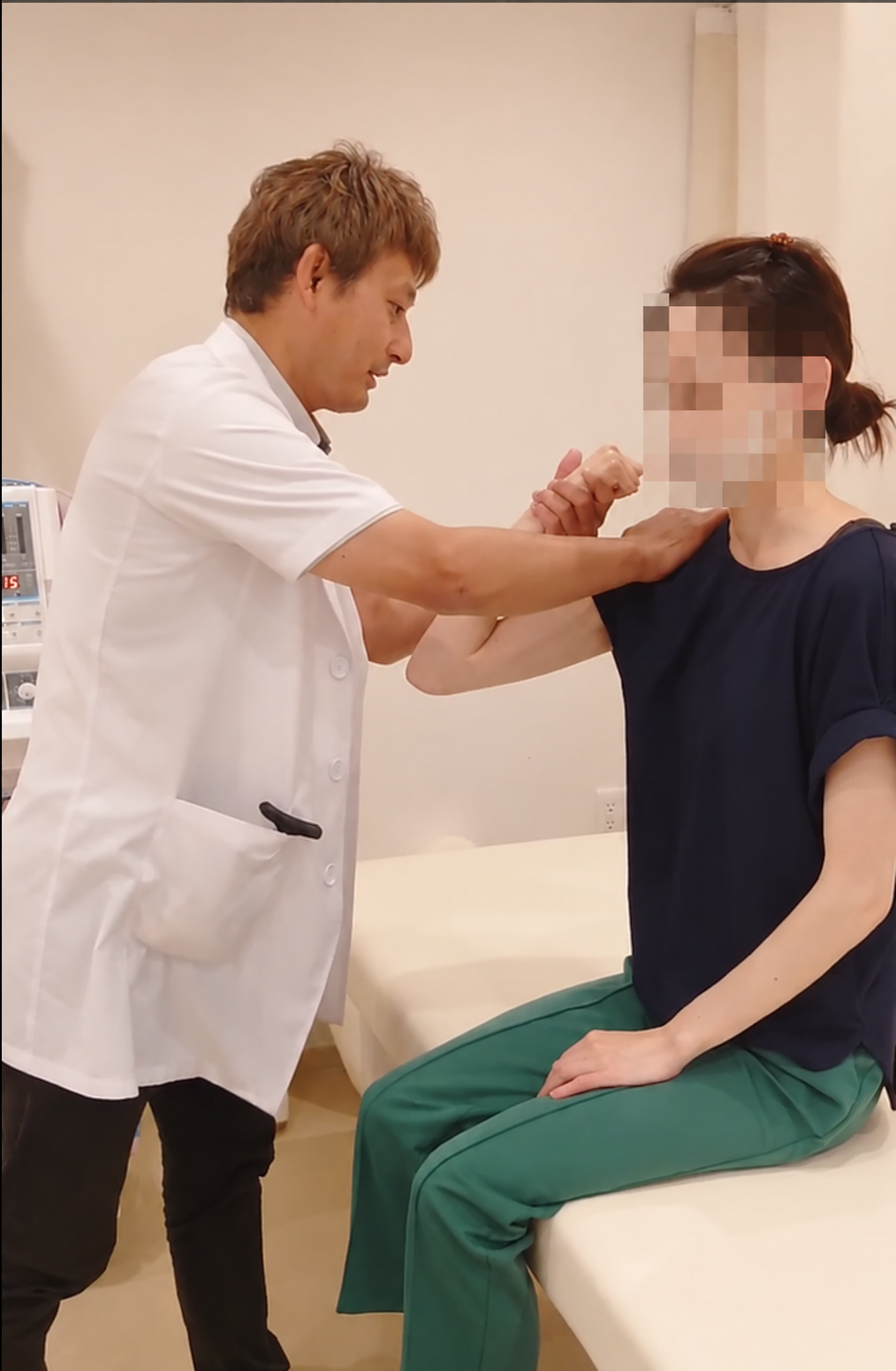 腕の力の入り方を確認する検査風景。患者さんの顔はモザイク処理済み